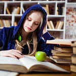 Woman Wearing Blue Jacket Sitting on Chair Near Table Reading Books